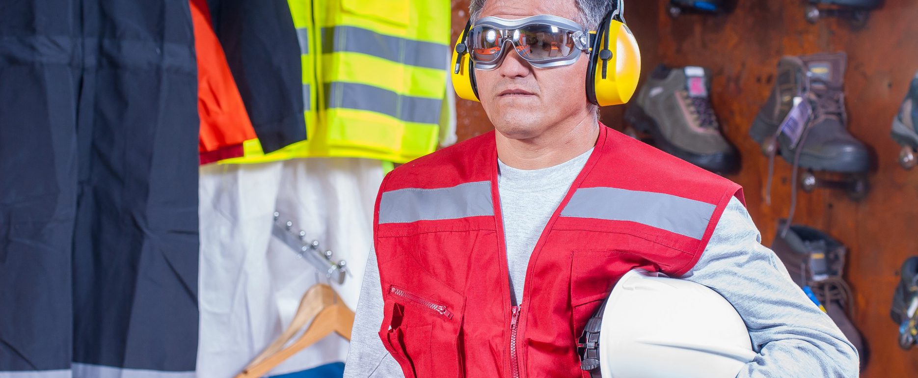 Industrial Deafness. Worker with helm under arm, googles, and hearing protection looking straight