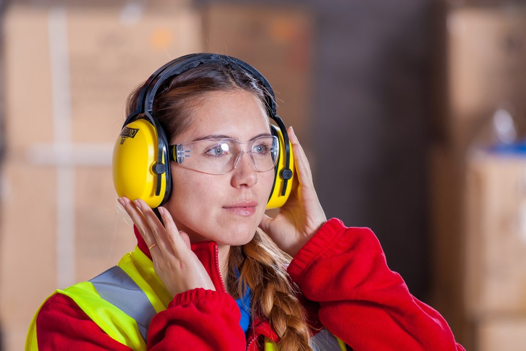 Woman with hearing protection headphones and googles at work.