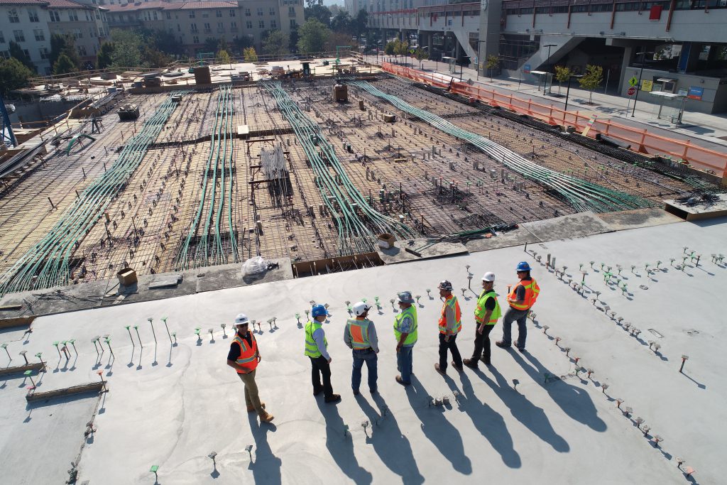 Seven workers standing on the newly built building watchg at the construction site.