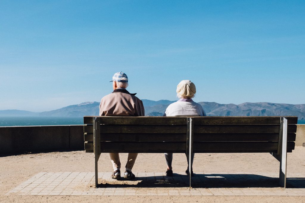 Old man and woman sitting on the bench and looking at the sea