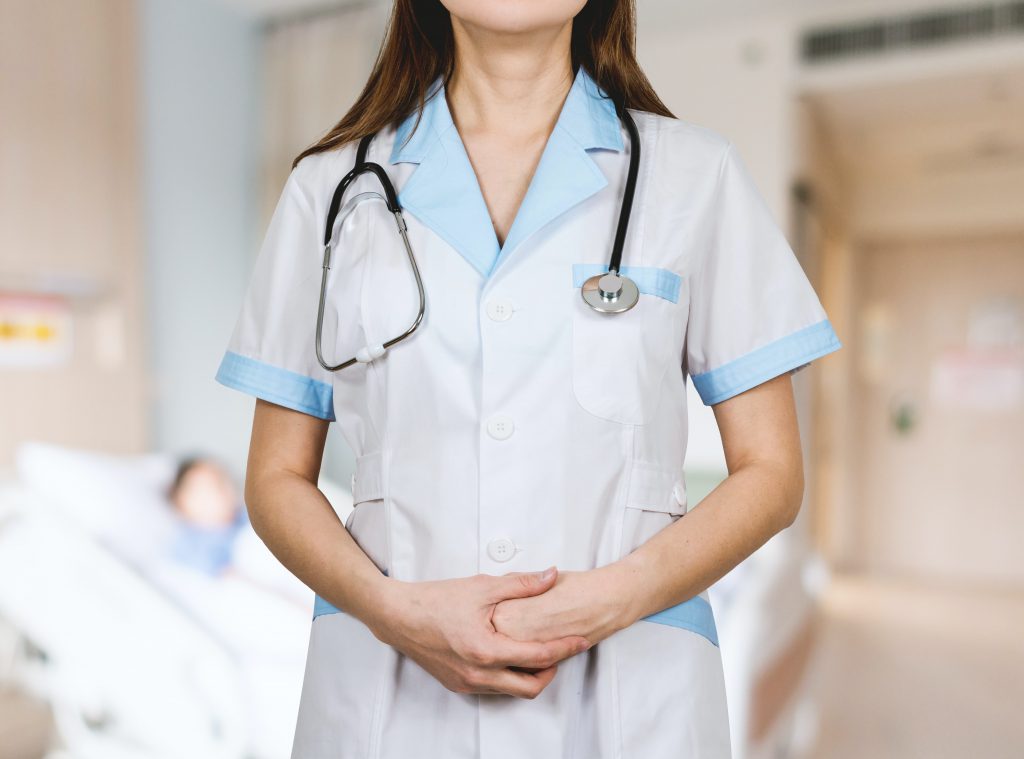 Nurse standing and watching strait to the camera with her hand on her stomach