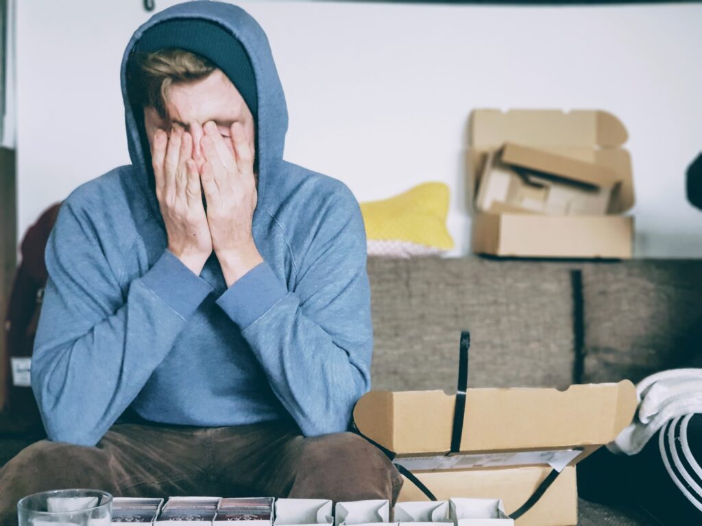 Stressed man with blue hoodie sitting on the couch